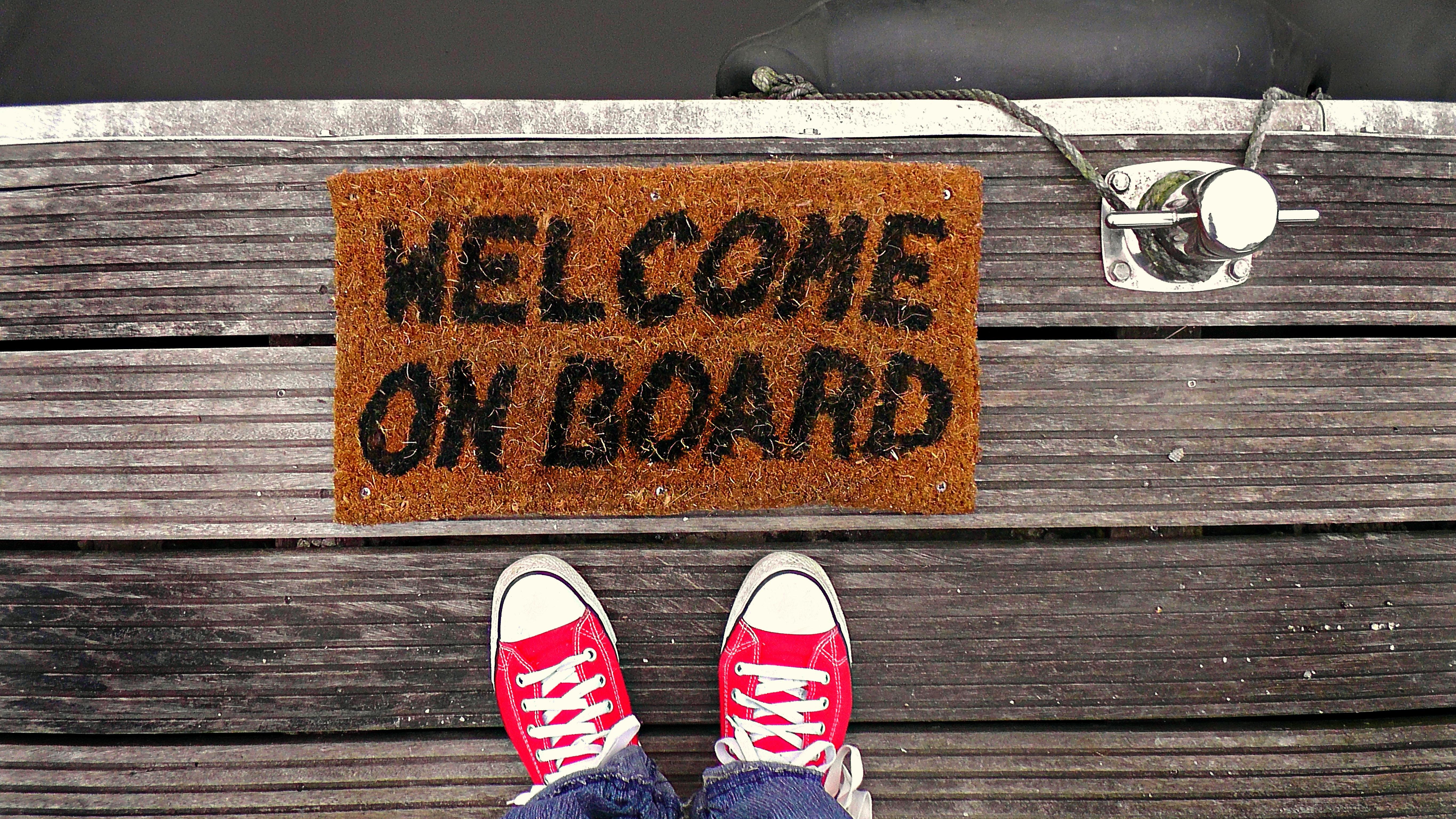 Feet in front of a doormat reading welcome on board
