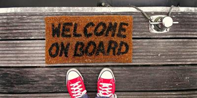 Feet in front of a doormat reading welcome on board