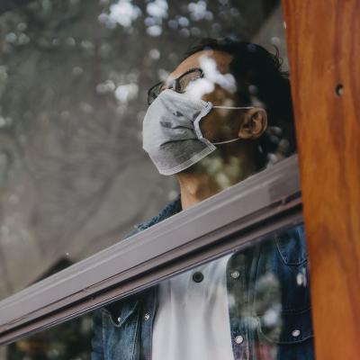 Masked man looking out a window